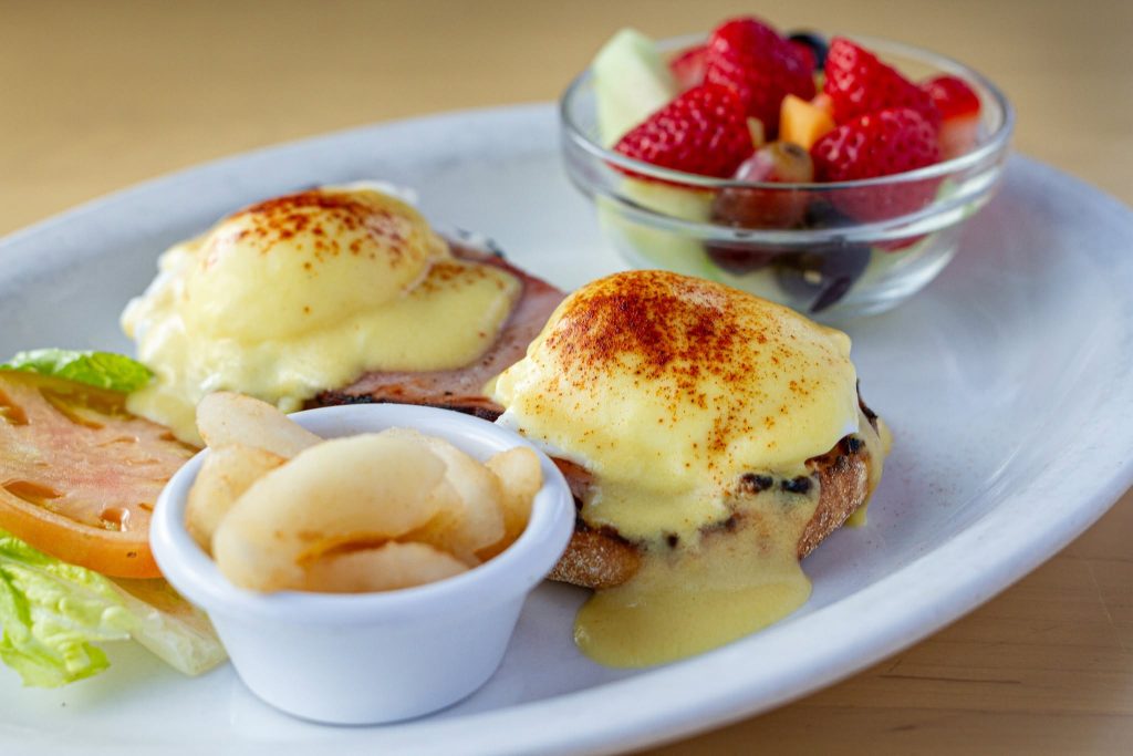 Eggs Benedict with hollandaise and a bowl of fresh fruit at Le Peep, a Valparaiso breakfast restaurant