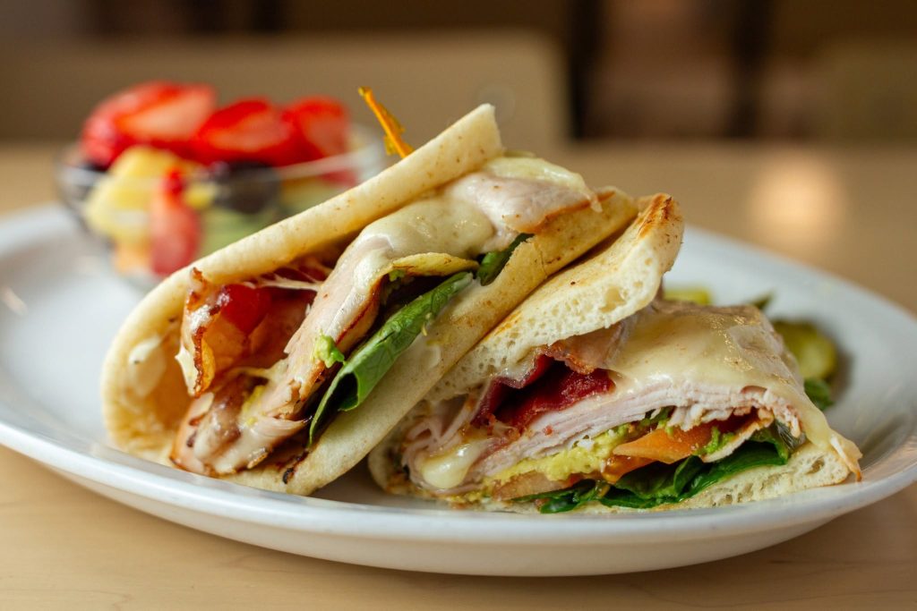 Turkey club on grilled flatbread with a side of fresh fruit at Le Peep Valparaiso
